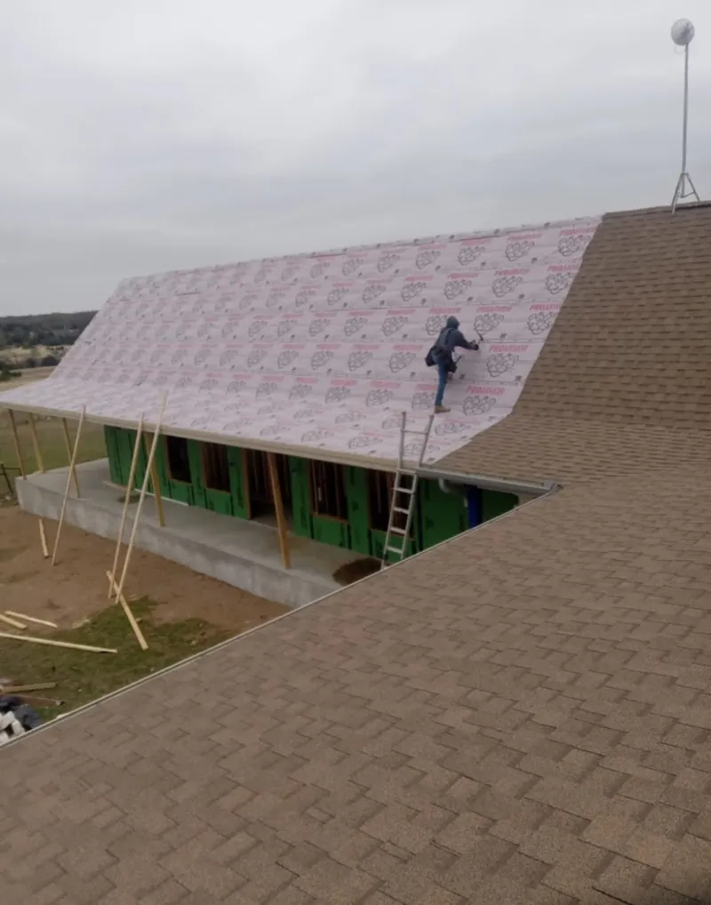 Worker preparing underlayment for a metal roof installation in Hanover